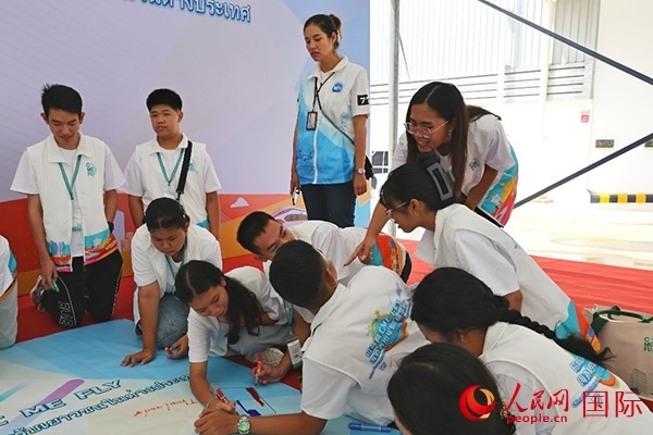 泰國學(xué)生在開營儀式展板上繪制圖案。人民網(wǎng)記者 白元琪攝