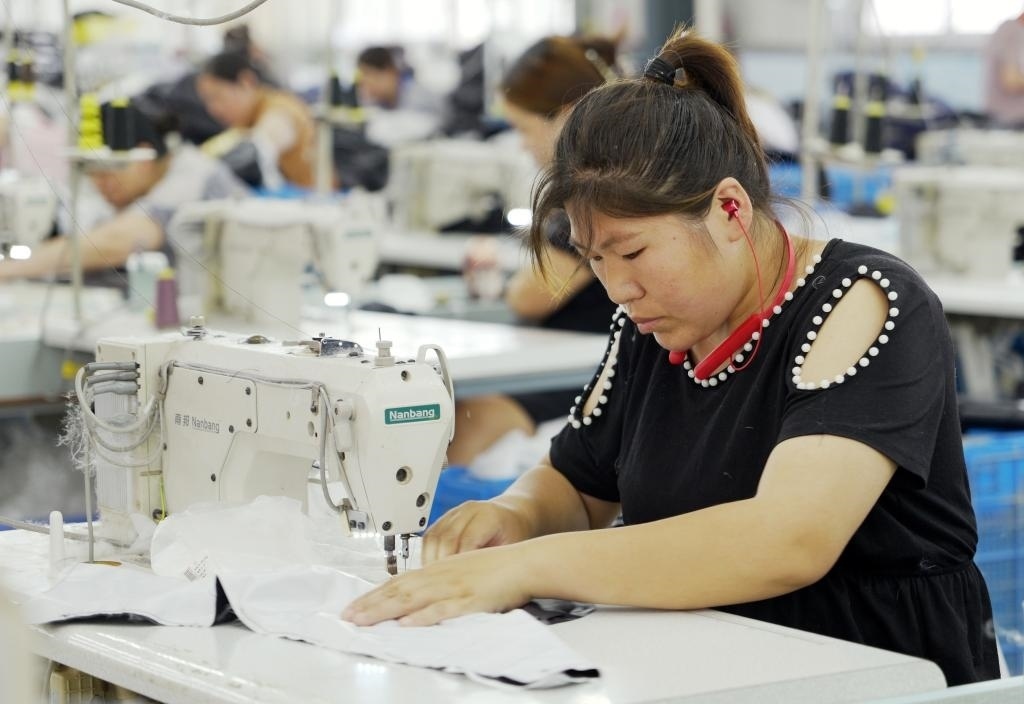 5月20日，村民在李寨村服裝加工廠內(nèi)忙碌。河南省周口市沈丘縣馮營鎮(zhèn)李寨村地處豫東平原。近年來，乘著脫貧攻堅與鄉(xiāng)村振興政策的東風(fēng)，李寨村積極探索產(chǎn)業(yè)發(fā)展模式，通過“龍頭企業(yè)+村集體經(jīng)濟+農(nóng)戶”的方式，逐漸發(fā)展形成肉牛養(yǎng)殖、設(shè)施農(nóng)業(yè)、服裝加工、康養(yǎng)民宿等產(chǎn)業(yè)，以產(chǎn)業(yè)振興助力鄉(xiāng)村振興。新華社記者 李嘉南 攝