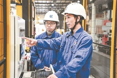 在廣西柳工機(jī)械股份有限公司生產(chǎn)車間內(nèi)，一名高級(jí)技師（右）給徒弟講解數(shù)控設(shè)備操作細(xì)節(jié)。新華社記者 曹祎銘攝