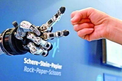 在德國漢諾威工博會上，參觀者與一款智能機器人進行“石頭剪子布”游戲。新華社發(fā)