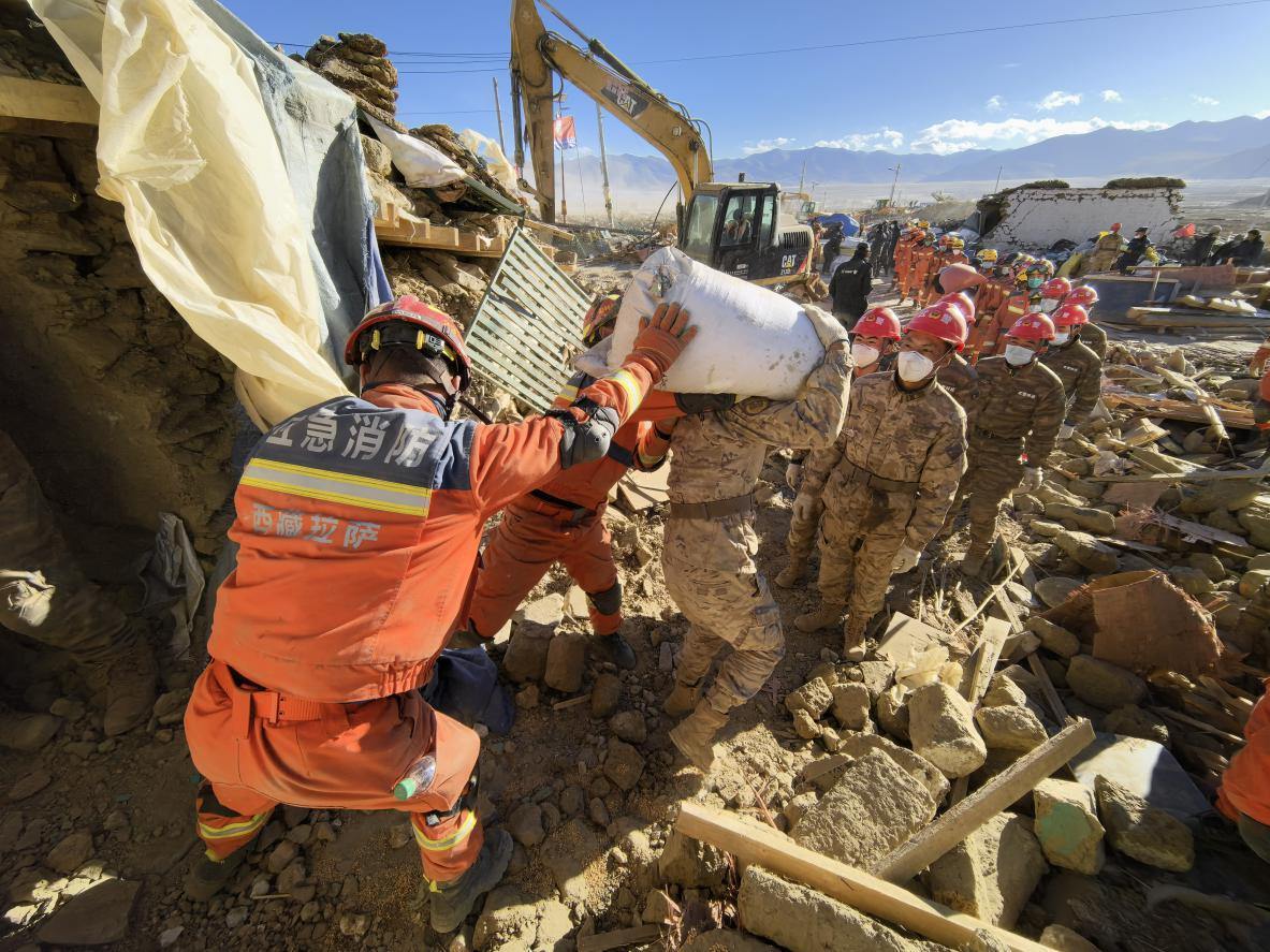 1月11日，定日縣長(zhǎng)所鄉(xiāng)古榮村，應(yīng)急消防等救援人員排隊(duì)接力搶運(yùn)掩埋在倒塌房屋下的群眾財(cái)物。人民日?qǐng)?bào)記者楊翹楚攝