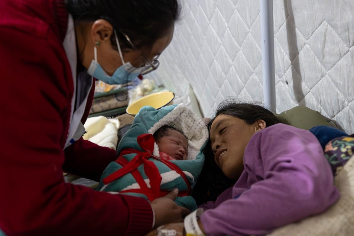 1月10日，定日縣中心醫(yī)院的婦產(chǎn)科醫(yī)生悉心照看一位母親和她懷里的新生兒。人民日?qǐng)?bào)記者張武軍攝