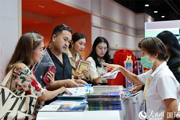 外國觀眾在中國展臺仔細(xì)閱讀赴華旅游介紹，向工作人員咨詢關(guān)于中國美食和景點的詳細(xì)信息。人民網(wǎng)記者 白元琪攝