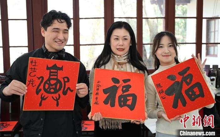 1月20日，外籍留學(xué)生和西泠印社社員李硯(中)展示各自創(chuàng)作的福貼。當日，來自巴西、馬來西亞、加納、哈薩克斯坦的外籍留學(xué)生在浙江杭州西泠印社體驗福貼、春聯(lián)和篆刻，感受古老的中國傳統(tǒng)文化。中新社記者 王剛 攝