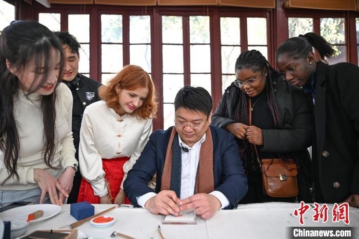 1月20日，篆刻家王臻向外籍留學(xué)生展示篆刻印章。當日，來自巴西、馬來西亞、加納、哈薩克斯坦的外籍留學(xué)生在浙江杭州西泠印社體驗福貼、春聯(lián)和篆刻，感受古老的中國傳統(tǒng)文化。中新社記者 王剛 攝