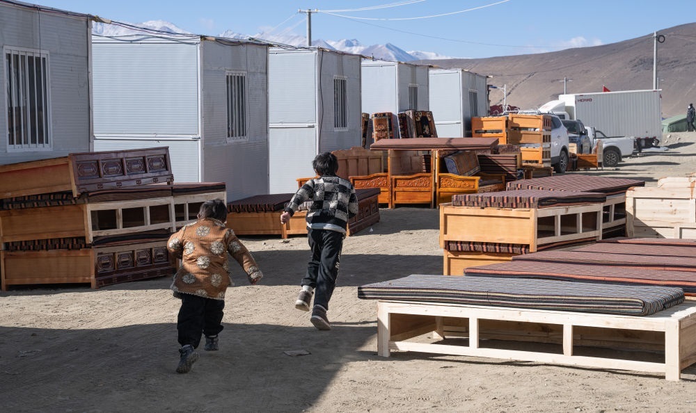 2025年1月13日，在定日縣嘎旦村，兩個孩子在剛運來的兩排藏床間奔跑。新華社記者丁增尼達 攝