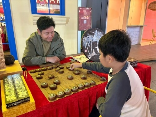 柯秋楓與市民下椰雕象棋。人民網(wǎng) 陳葉欣攝