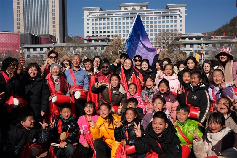 中外青年學(xué)子在安塞文化廣場觀看陜北腰鼓和大秧歌表演后合影留念，大家踏著鼓點共舞，翻飛的紅綢與躍動的身影交織，在黃土地廣場上繪出一幅生動的陜北民俗互動畫卷