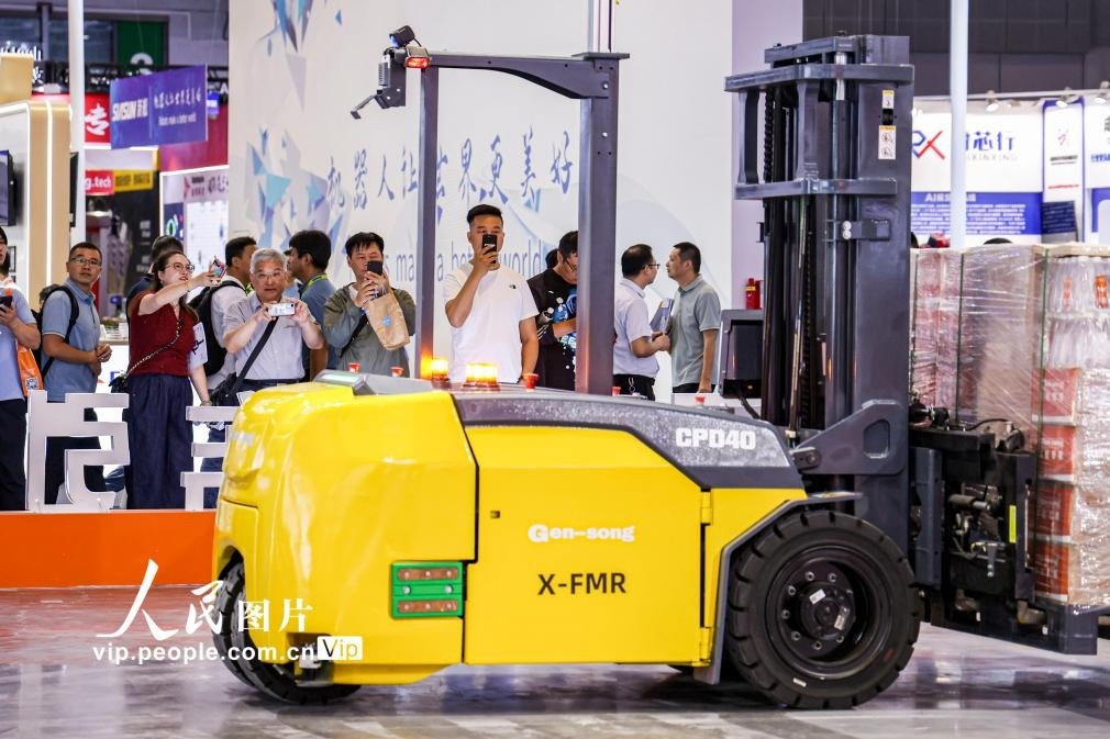 第24屆中國工博會現(xiàn)場，觀眾觀看叉取機器人作業(yè)演示。王初攝（人民圖片網(wǎng)）