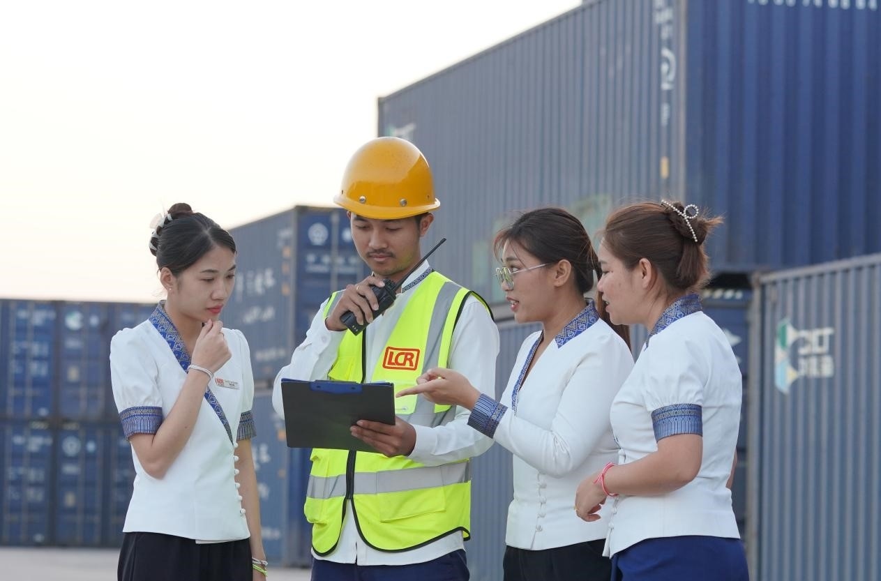 萬象南站貨運(yùn)值班員陳尼啦（左一）與同事在一起討論工作。老中鐵路有限公司供圖