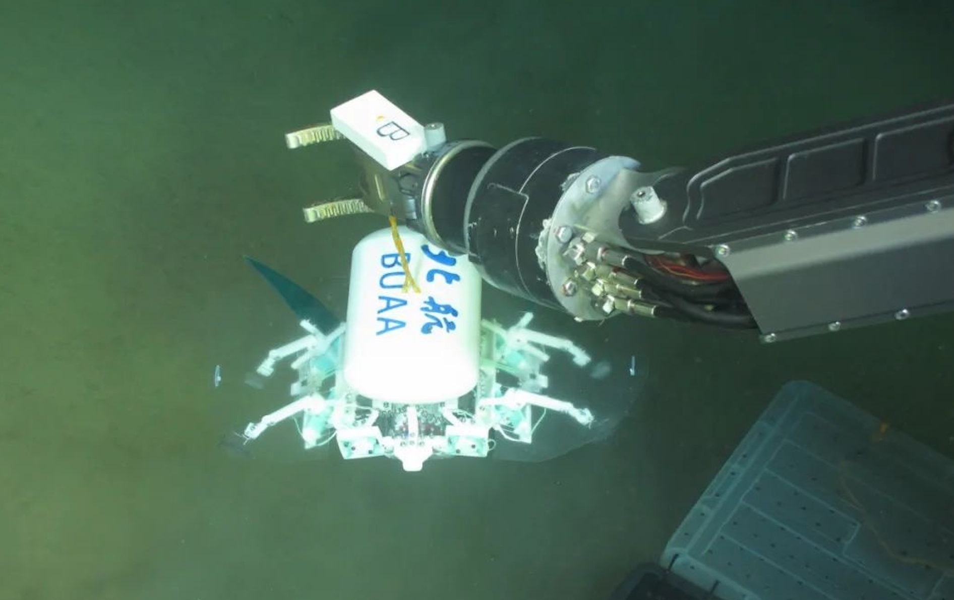 科研人員利用機械臂將北航深海小型機器人投于馬里亞納海溝。校方供圖