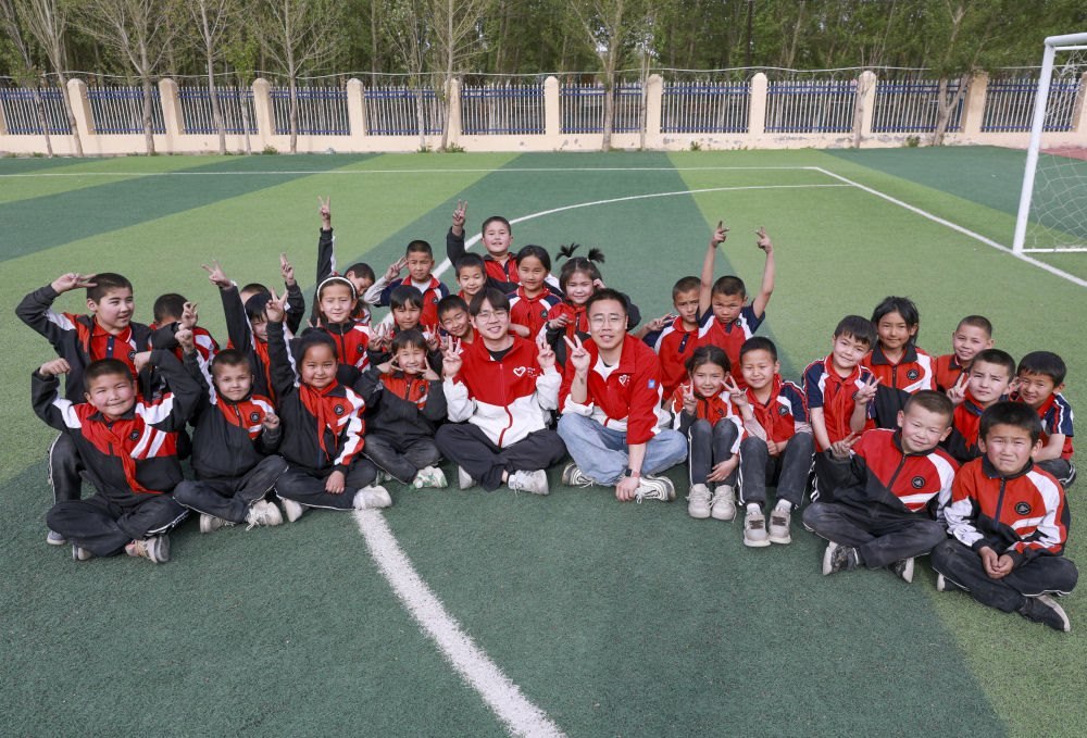 4月23日，在新疆克州阿圖什市哈拉峻鄉(xiāng)謝依特小學，支教教師王俊文（中左）、李軻凡（中右）和學生在一起。