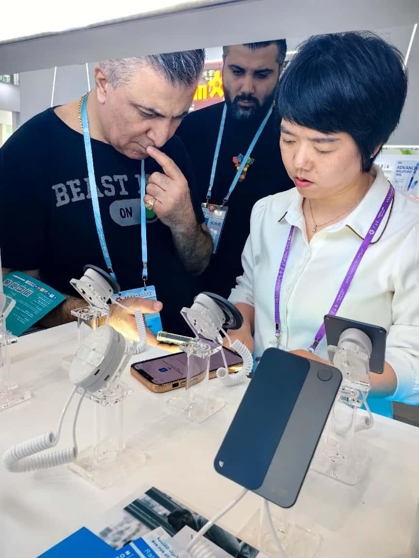展臺工作人員向外商展示“AI TOP翻譯終端”。圖片來源：受訪者提供