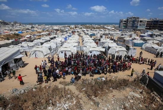 5月28日，人們?cè)诩由吵俏鞑康纳程犭y民營(yíng)等待領(lǐng)取救助食物。新華社發(fā)（里澤克·阿卜杜勒賈瓦德攝）